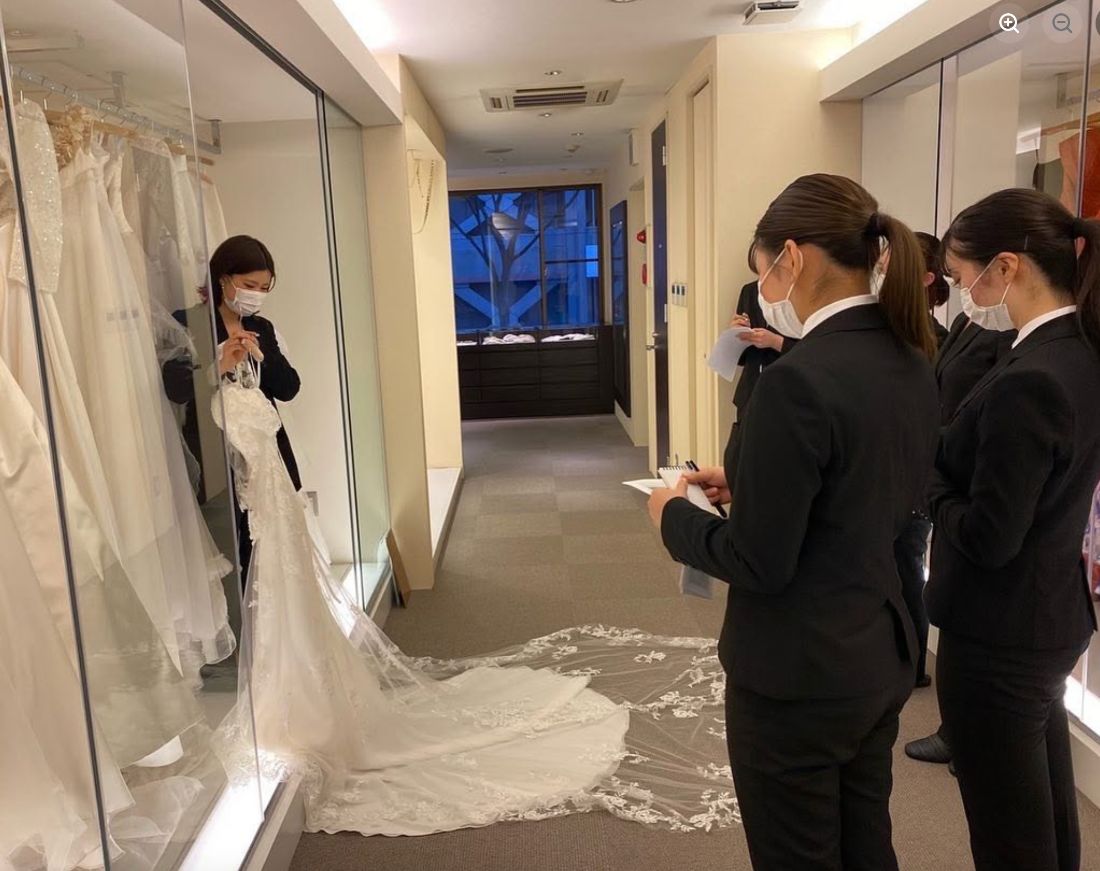 ドレスの説明を受けながらメモを取る学生たち