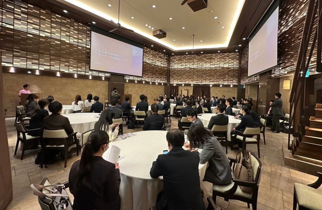 円卓が並ぶ会場でセミナーを聴講する参加者