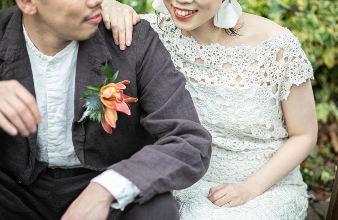 ガーデンで寄り添う新郎新婦。手作りの衣裳とブートニア