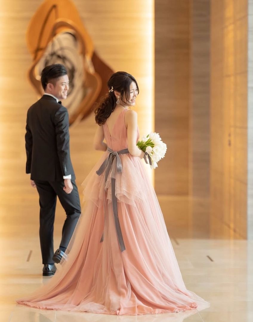 ピンクのドレスでブーケを手にほほえむ新婦と新郎