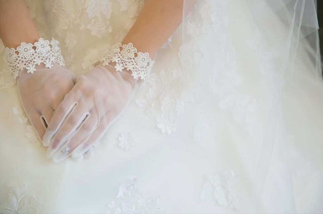 レースのグローブをまとった新婦の手元とウェディングドレス