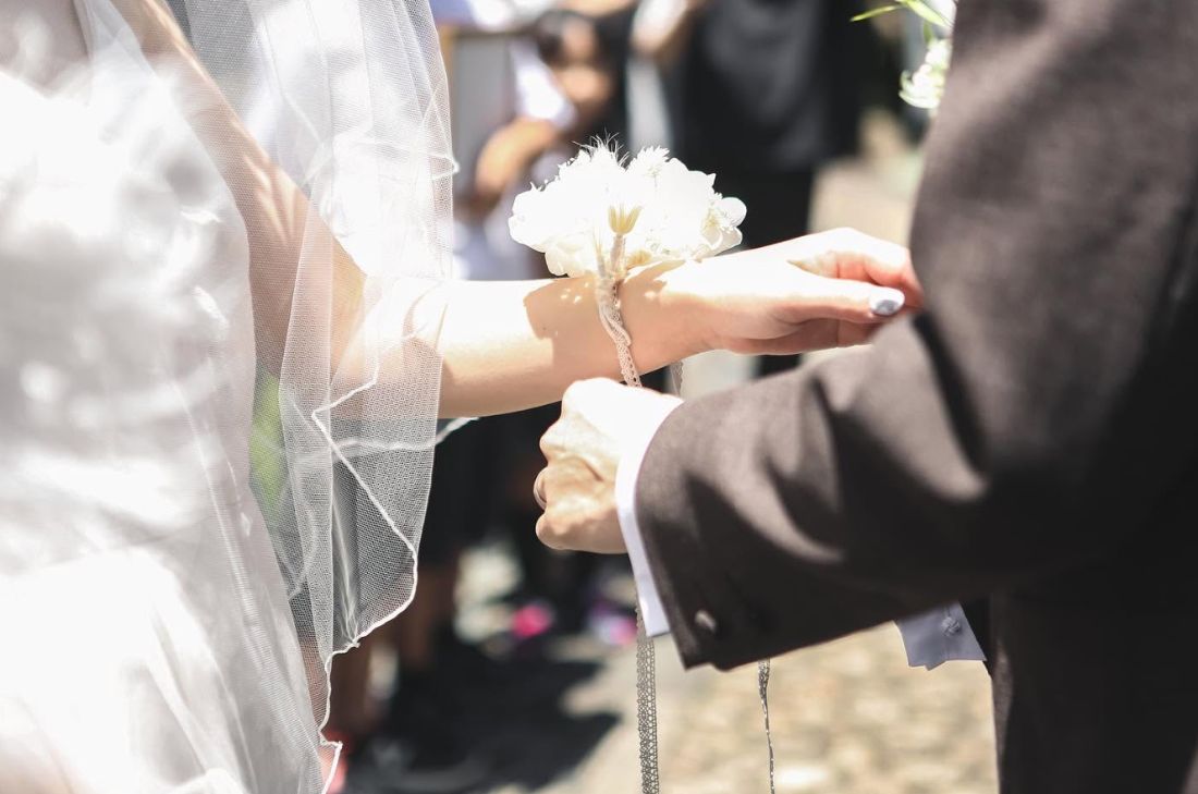 挙式後、新婦の手首にリストブーケを結ぶ場面