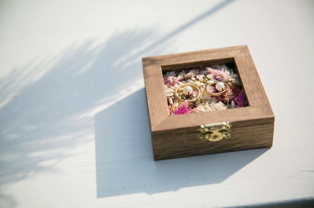 ドライフラワーを敷き詰めた木製リングケースと結婚指輪