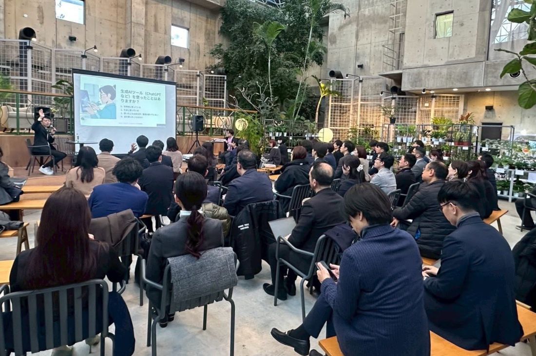 生成AIセミナーで挙手を求める場面。満席の会場